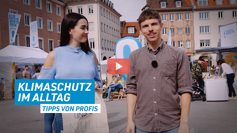 Sarah und Christian stehen auf dem Rathausplatz in Würzburg. Unten links im Bild steht der Schriftzug: Klimaschutz im Alltag - Tipps von Profis