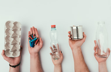 fünf Hände halten jeweils Eierpappkarton, Batterien, Platikflasche, Weißblechdose und Milchflasche